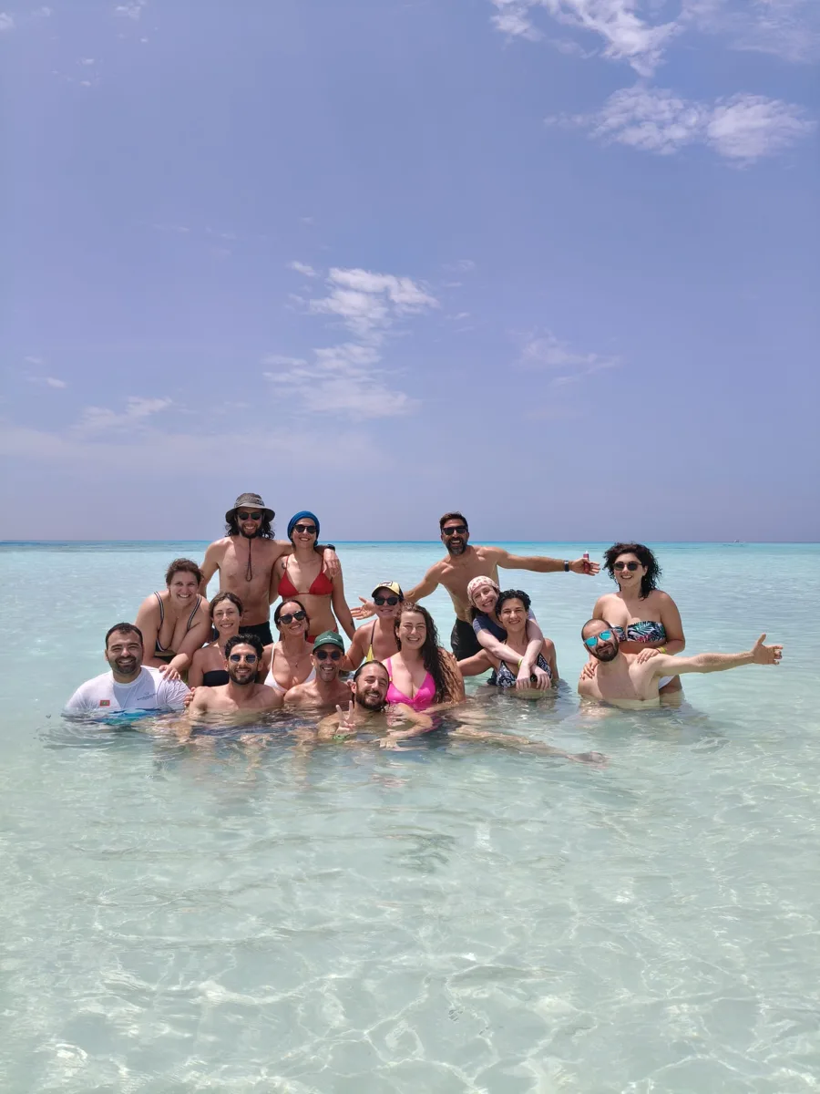 Il gruppo di viaggiatori sorride nell’acqua cristallina di una lingua di sabbia a Keyodhoo, Maldive